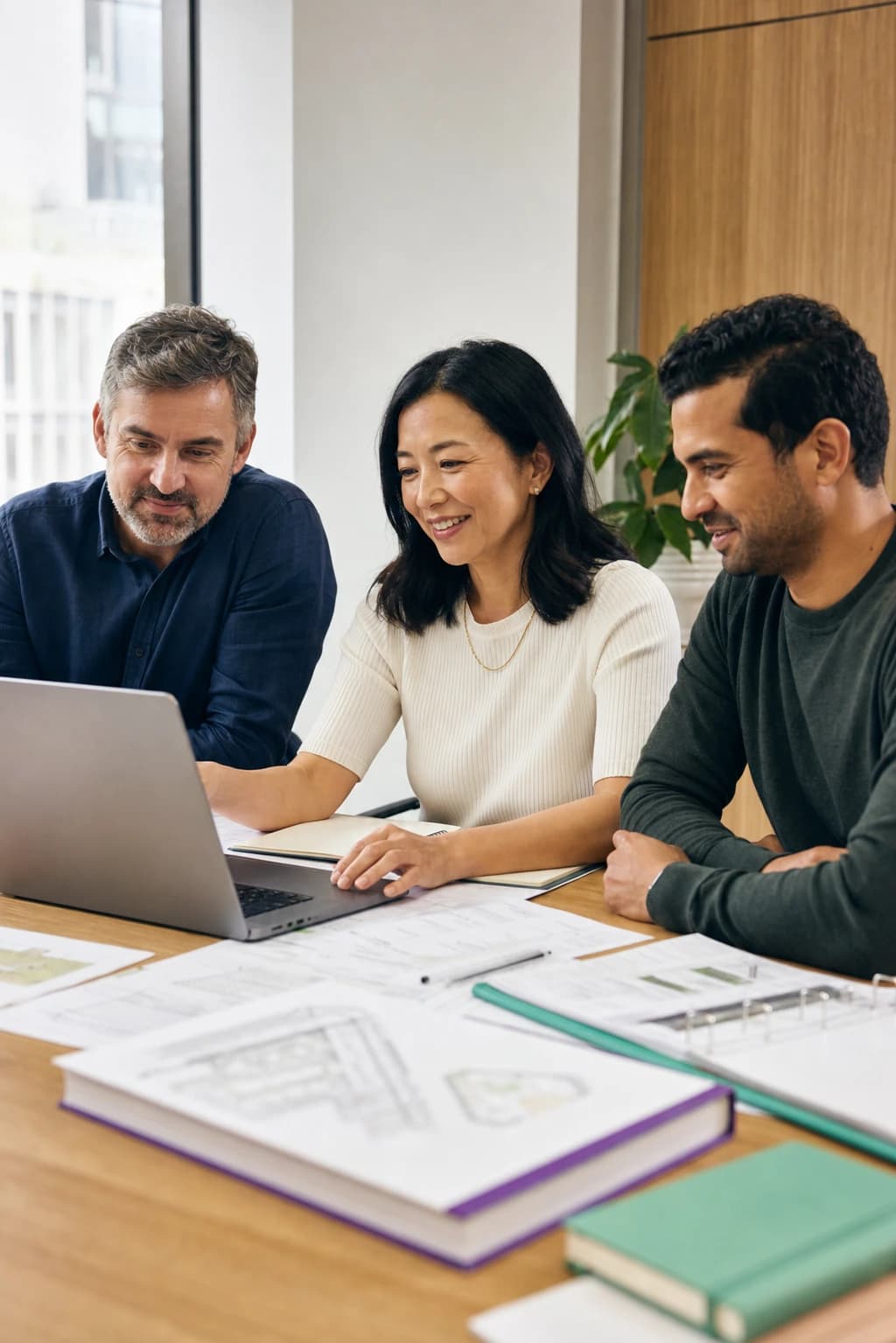 Three delivery professionals reviewing a live engagement together around a laptop