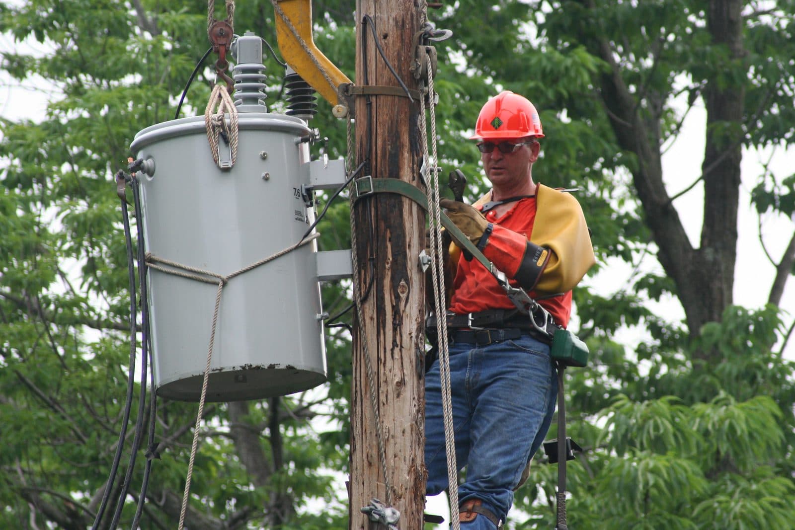 A line worker installing a transformer on a utility pole