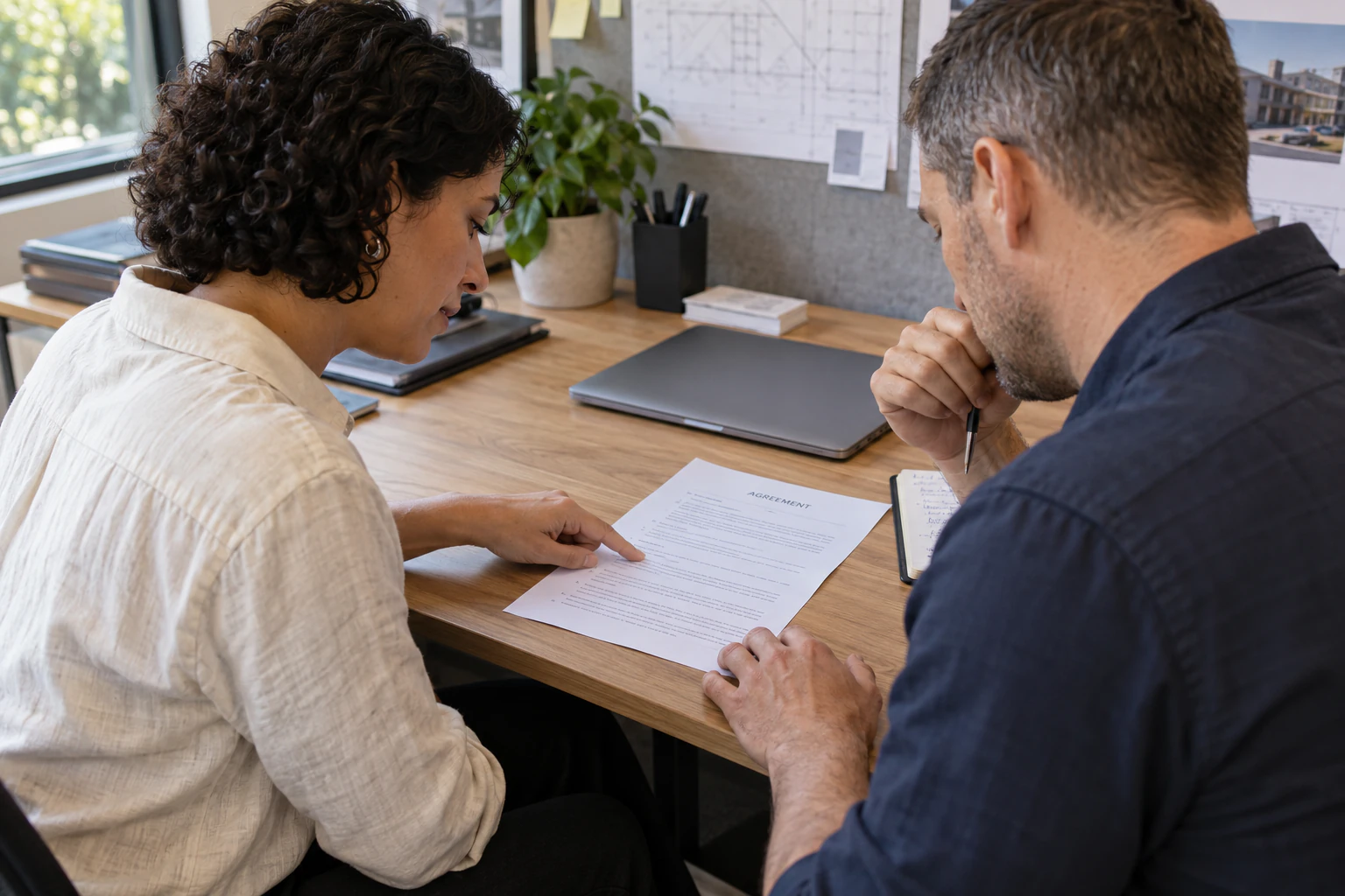 Two delivery professionals review an agreement at an office desk.